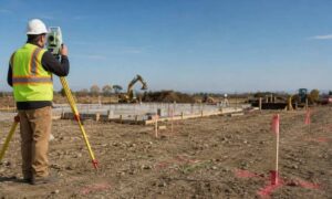 Surveyor using a total station to complete a construction survey on an active Vermont construction site