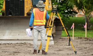 Surveyor using a total station at a construction site for construction staking survey work